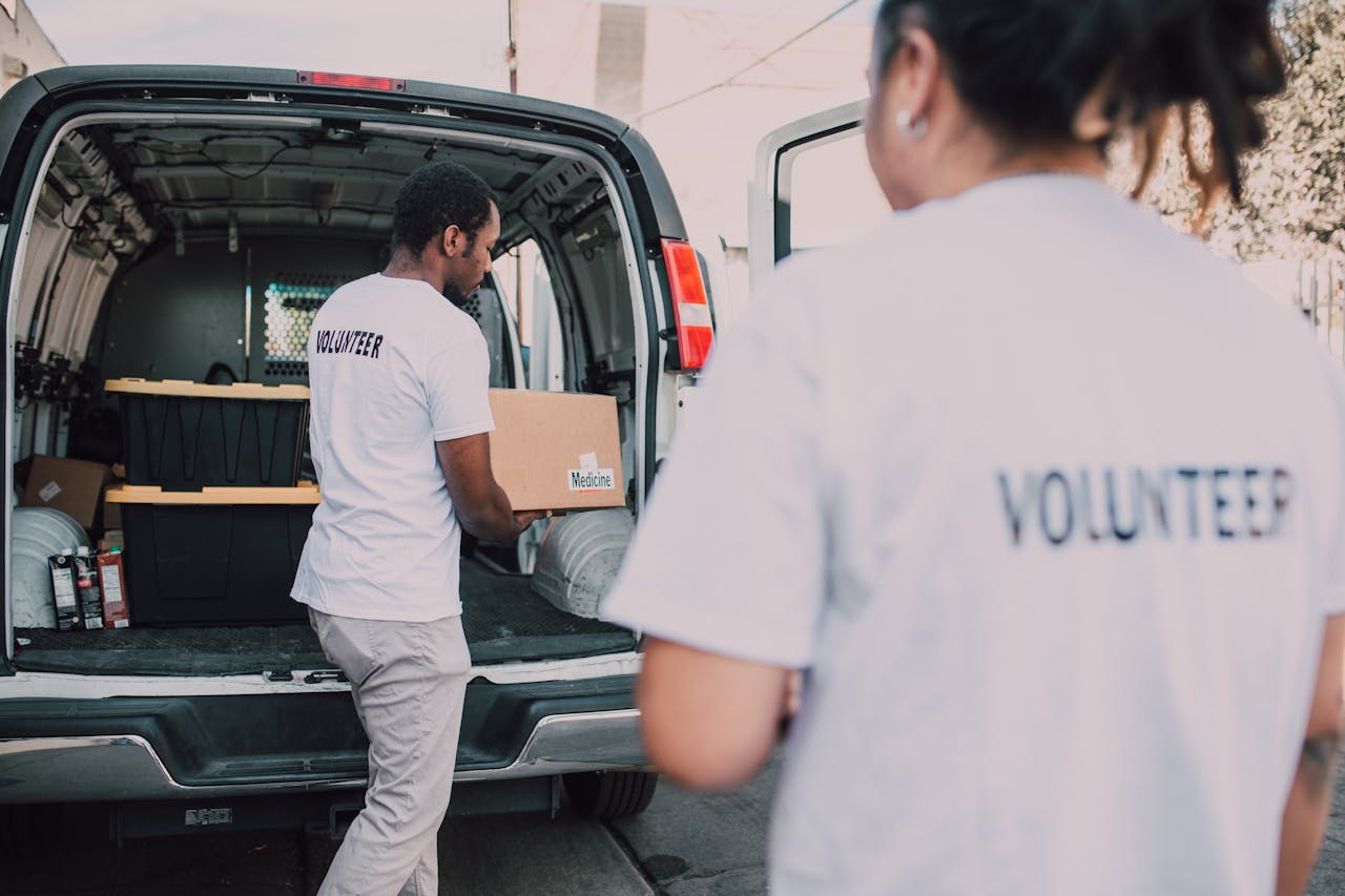 Volunteers loading medicine supplies into a van for donation and distribution.